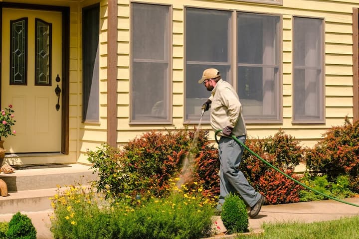 Pest Control service spraying a homes perimeter.